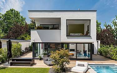 Modernes zweigeschossiges Haus mit Terrasse, Garten und Pool im Außenbereich.