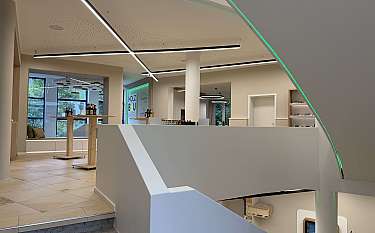 Modern gestalteter Innenraum mit Treppe, Beleuchtung und Verkaufstischen.